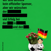 Grüner Blumen-Mankopf-Post mit geschwärztem Glückwunschtext und Fußball-Pflanzgefäß mit Deutschlandfahne.